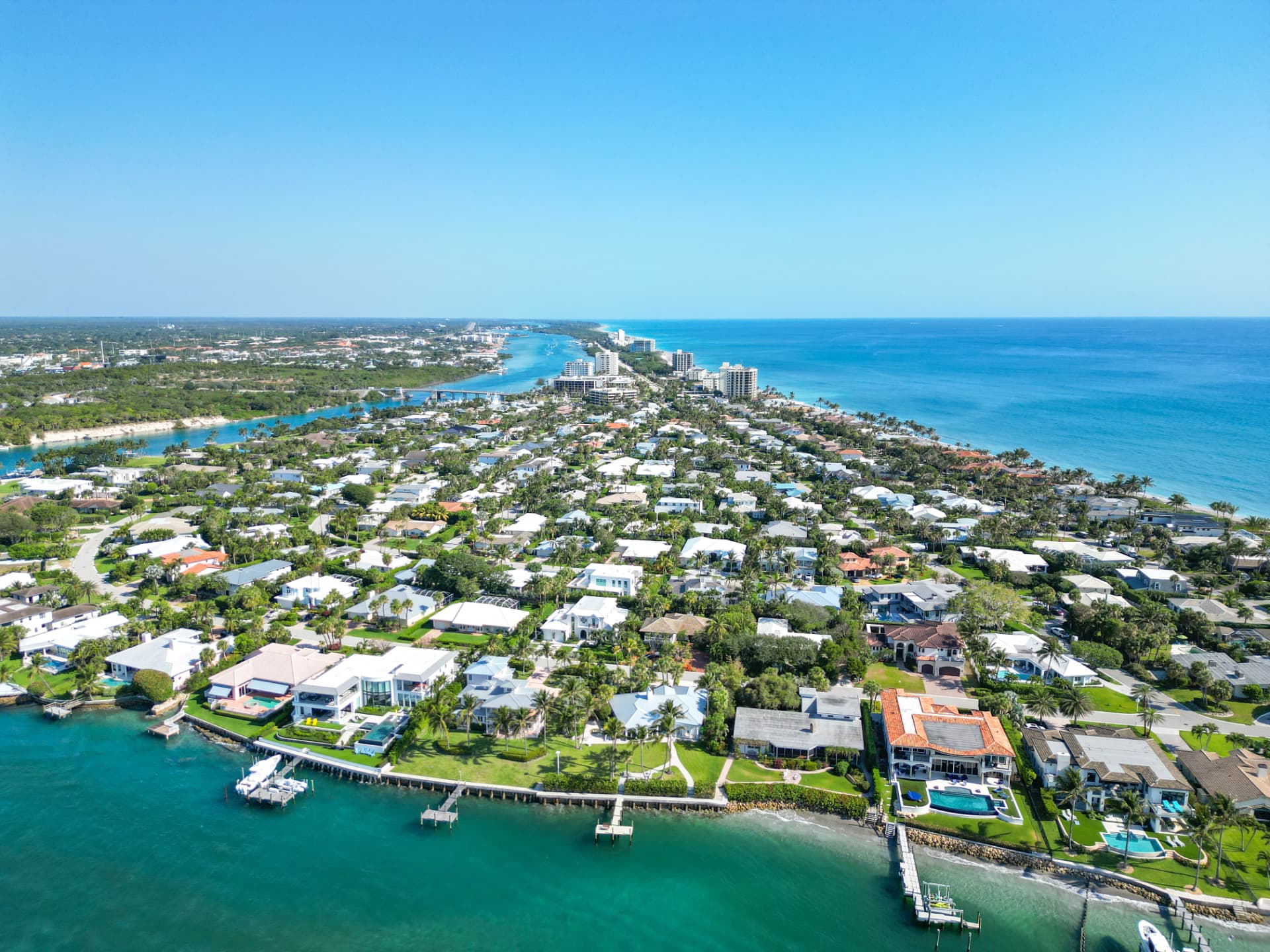 Aerial view of a coastal residential peninsula in Jupiter, Florida, with single-family homes, docks along the intracoastal waterway and the Atlantic shoreline beyond